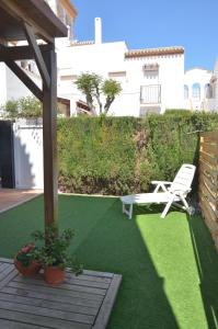 eine Terrasse mit einem Stuhl und einer Bank auf dem Rasen in der Unterkunft Apartamento 700 metros de la playa in Playa Flamenca