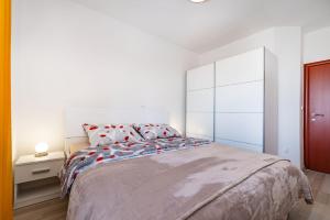 ein weißes Schlafzimmer mit einem großen Bett mit roten Kissen in der Unterkunft Apartments Sandra in Turanj