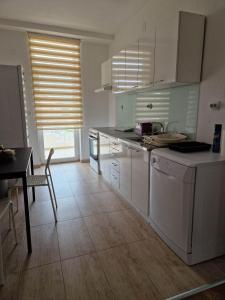 a kitchen with white cabinets and a table and a dining room at Town Square House in Gevgelija