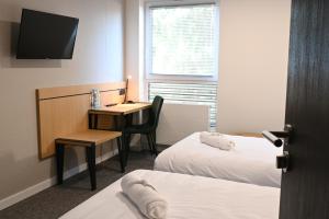 a hotel room with two beds and a desk and a television at Hotel Parrot in Raszyn