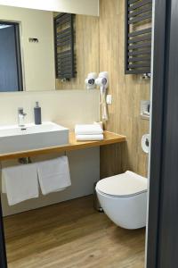 ein Badezimmer mit einem Waschbecken, einem WC und einem Spiegel in der Unterkunft Hotel Parrot in Raszyn