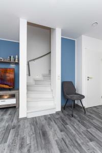a living room with white stairs and a chair at Ferienhaus Ella in Dornumersiel
