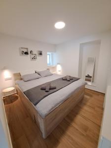 Cama grande en habitación blanca con suelo de madera en Apartman Tea, en Mali Lošinj