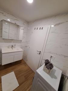 a white bathroom with a shower and a sink at Apartman Tea in Mali Lošinj
