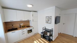 a kitchen with white cabinets and a sink and a tv at Apartman Tea in Mali Lošinj +4 photos