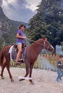 Una mujer está montando un caballo en una báscula. en Thethi Mountain, en Theth
