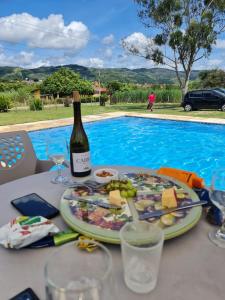 a table with a plate of food and a bottle of wine at Casa com piscina aquecida, privativa,diarista, em condomínio, Bonito-Pe in Bonito