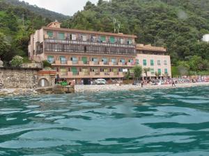 - un bâtiment sur une plage à côté d'une étendue d'eau dans l'établissement Hotel Capo Noli, à Noli