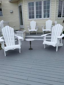 three white rocking chairs sitting on a porch at Phare des Dunes Lighthouse in Tracadie