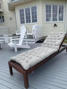 a bench on a porch with two white chairs at Phare des Dunes Lighthouse in Tracadie