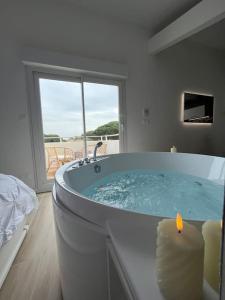 a bathroom with a bath tub with a candle in it at Lovicéa Balnéo Suite, 200m plage in Le Grau-dʼAgde
