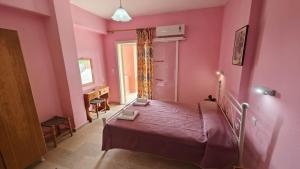 een slaapkamer met roze muren en een bed in een kamer bij Elena Pool in Agios Georgios