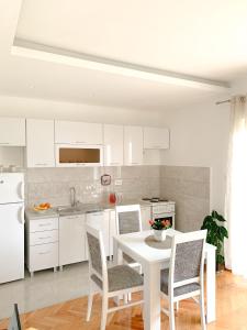 a white kitchen with a white table and chairs at Talija Apartments in Bijela