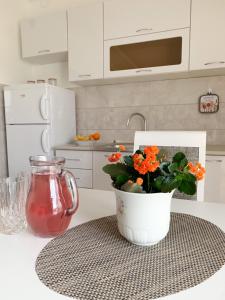 a white kitchen with a vase with orange flowers on a counter at Talija Apartments in Bijela