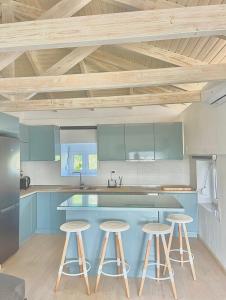 una cocina con armarios azules y taburetes. en WoodHome, en Kalamitsi