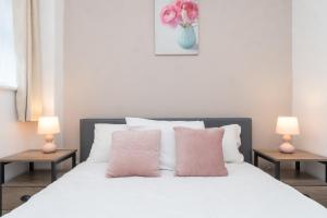 a bedroom with a white bed with pink pillows at Spacious 2 bed Southville flat near Harbourside in Bristol