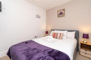 a bedroom with a bed with a purple blanket on it at Spacious 2 bed Southville flat near Harbourside in Bristol