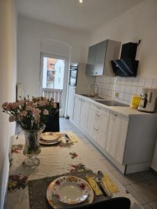 una cocina con una mesa con platos y flores. en Käthe-Kollwitz-Straße 54, F2, en Altemburgo