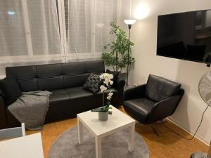 un soggiorno con divano in pelle nera e tavolo di City Centre Studio a Basilea
