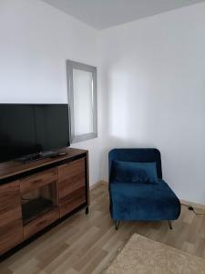 a living room with a tv and a blue chair at Apartament Paderewskiego 1 in Zielonka +3 photos