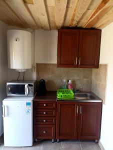 a kitchen with wooden cabinets and a white refrigerator at Két Kerék Vendégház in Patvarc