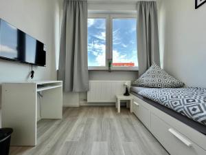 a bedroom with a bed and a tv and a window at Trippel M Apartments Stuttgart Zuffenhausen in Stuttgart