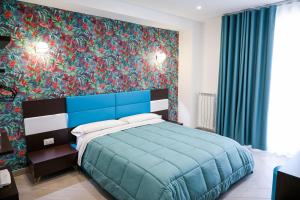 sypialnia z niebieskim łóżkiem i kolorową ścianą w obiekcie Palazzo Archeo w mieście Pompeje