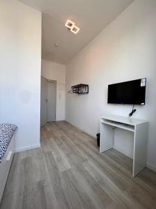a bedroom with a desk and a tv on a wall at Nujen- Hotel und Apartment Stuttgart Zuffenhausen in Stuttgart