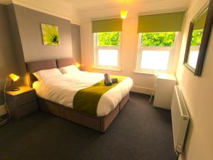 a bedroom with a large bed with two windows at Amazing 2 bed London apartment in London