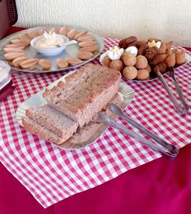 una mesa con platos de comida en un mantel rojo y blanco en Pousada Três Praias, en Guarapari