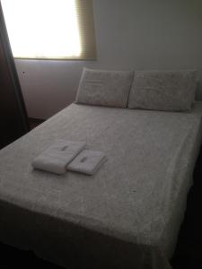 a bed with two towels sitting on top of it at Aconchego bem localizado in Varginha