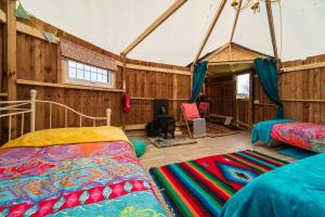 a bedroom with two beds in a room with wooden walls at Mad Hatters Glamping & Campsite in Ely