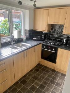 a kitchen with wooden cabinets and a sink and a stove at Family Home Near City Centre in Carlisle