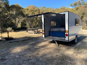 a small white trailer parked in a park at Jindabyne caravan hire in Jindabyne