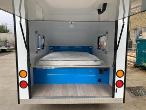 Jindabyne caravan hire في جيندابين: سرير في خلف سيارة فان زرقاء وبيضاء