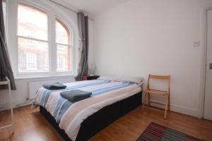 a bed in a room with a window and a chair at Great flat located in trendy Soho in London