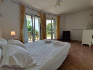 a large white bed in a room with windows at Sea Satin Anavyssos in Anavissos