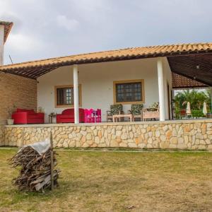 a house with a stone wall in front of it at Casa com piscina aquecida, privativa,diarista, em condomínio, Bonito-Pe in Bonito