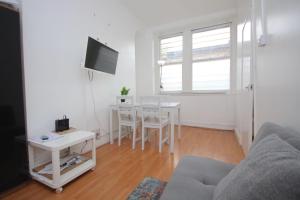 Great flat located in trendy Soho في لندن: غرفة معيشة بيضاء مع طاولة وتلفزيون