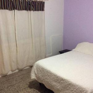 1 dormitorio con cama blanca y cortina blanca en Pellegrini Departamentos muy confortable y bien ubicado en Godoy Cruz