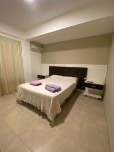 Un dormitorio con una cama con toallas moradas. en Alojamiento Necochea en La Banda