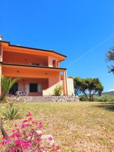 an orange house with flowers in front of it at Casa Mamà in Portixeddu