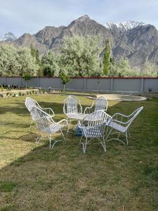 un groupe de chaises assises dans l'herbe avec des montagnes dans l'établissement Royal Resort Skardu, à Skardu