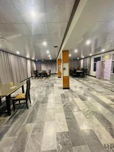 une grande chambre avec des tables et des chaises dans un bâtiment dans l'établissement Royal Resort Skardu, à Skardu