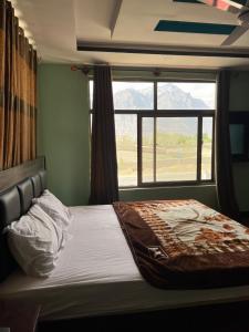 - une chambre avec un lit et une grande fenêtre dans l'établissement Royal Resort Skardu, à Skardu