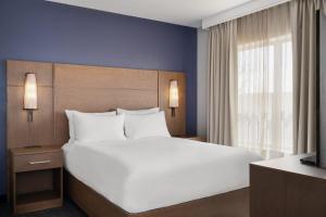 a bedroom with a large white bed and a window at Residence Inn by Marriott Chicago Naperville/Warrenville in Warrenville