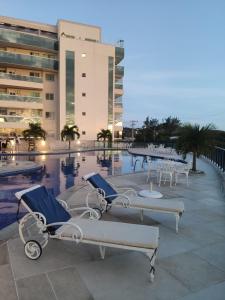 a swimming pool with chairs and a table in front of a building at Le Bon Vivant, Nosso Lar in Arraial do Cabo
