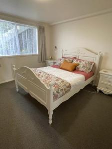 1 dormitorio con cama blanca y ventana en Westland Apartment en Dunedin