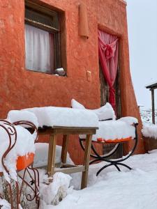 une table et des chaises recouvertes de neige devant un bâtiment dans l'établissement Mamuna Posada un lugar para disfrutar de a dos, à Uspallata