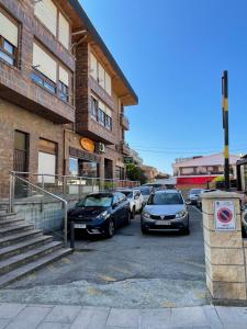 ein Parkplatz mit vor einem Gebäude geparkten Autos in der Unterkunft Apartamento Recién Reformado en Somo junto iglesia in Somo